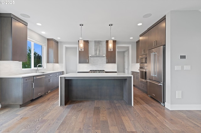 13560 SW Whitworth Ct, Beaverton, OR 97005 - kitchen featuring stainless steel appliances, wall chimney range hood, a kitchen island, light countertops, and decorative backsplash