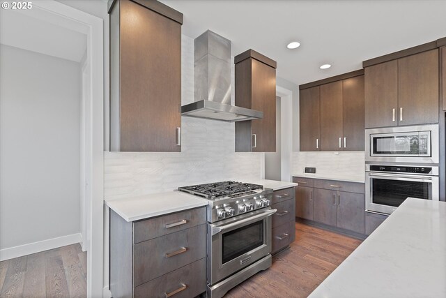 13560 SW Whitworth Ct, Beaverton, OR 97005 - kitchen featuring stainless steel appliances, wall chimney exhaust hood, wood finished floors, dark brown cabinets, and recessed lighting