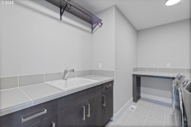 13560 SW Whitworth Ct, Beaverton, OR 97005 - laundry area featuring washing machine and dryer, baseboards, light tile patterned floors, and cabinet space
