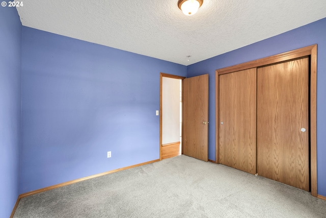 unfurnished bedroom featuring a closet, a textured ceiling, and light colored carpet