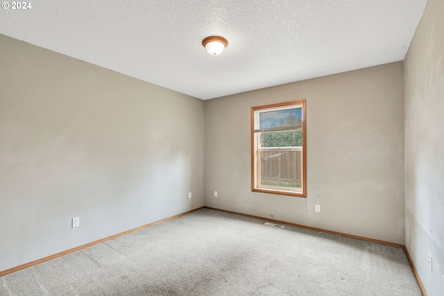 carpeted empty room featuring a textured ceiling