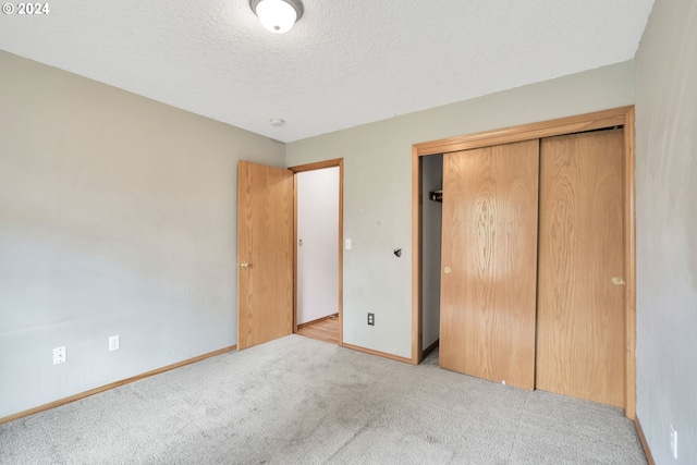 unfurnished bedroom with a textured ceiling, light colored carpet, and a closet