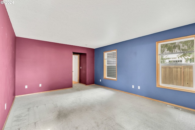 carpeted empty room with a textured ceiling