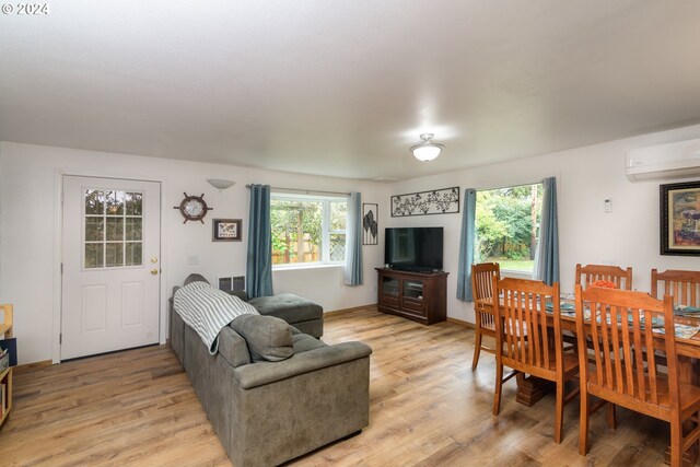 living room with an AC wall unit and light hardwood / wood-style floors