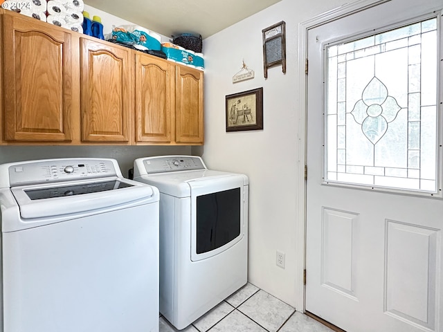 laundry area with separate washer and dryer, light tile patterned floors, plenty of natural light, and cabinets