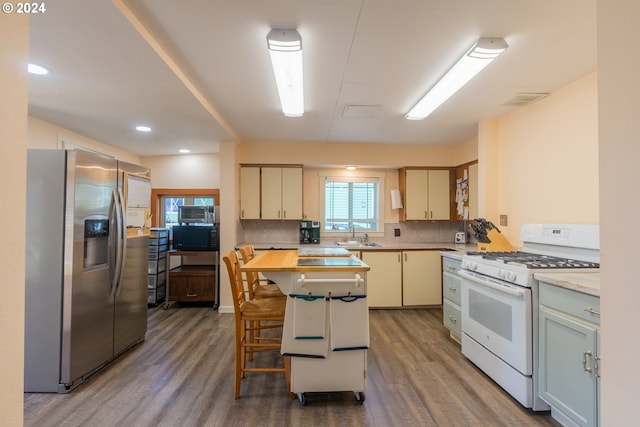 kitchen featuring hardwood / wood-style flooring, white gas range, a kitchen island, and stainless steel fridge with ice dispenser