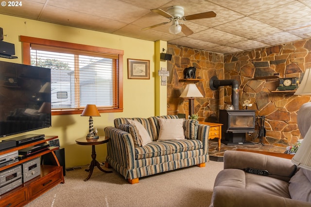 carpeted living room with a wood stove and ceiling fan