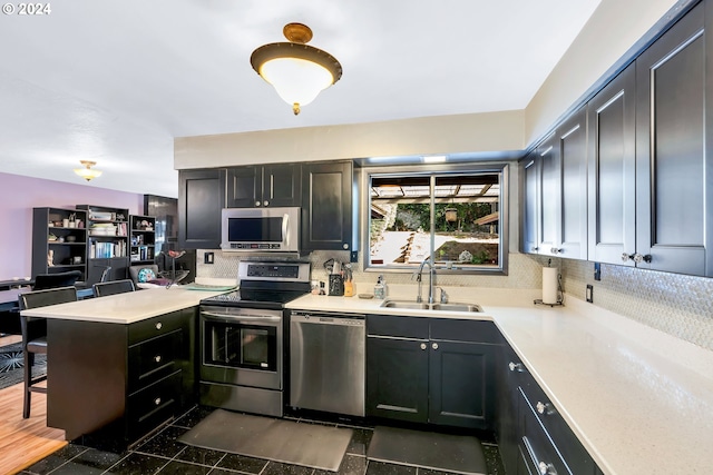 kitchen featuring kitchen peninsula, sink, tasteful backsplash, dark wood-type flooring, and stainless steel appliances