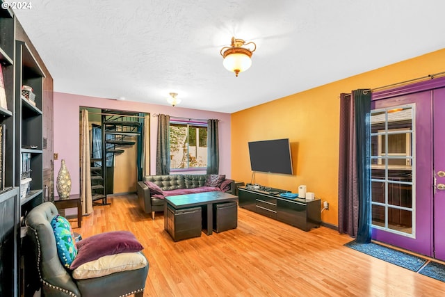 living room with light wood-type flooring, french doors, and a textured ceiling