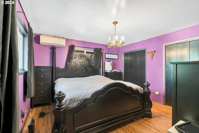 bedroom with a wall unit AC, an inviting chandelier, and light hardwood / wood-style flooring