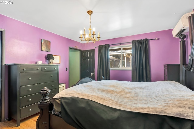 bedroom featuring a wall mounted air conditioner, a chandelier, and light wood-type flooring