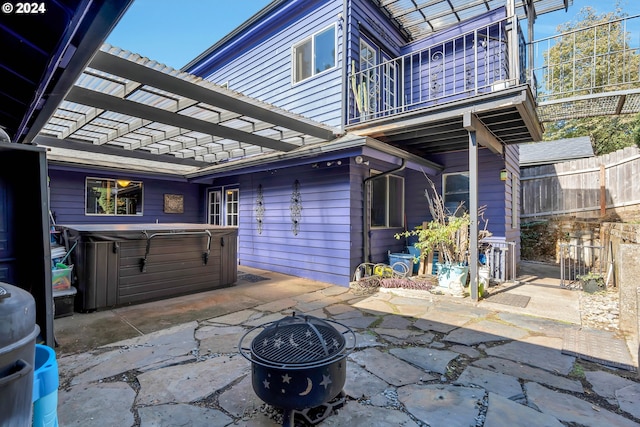 view of patio / terrace featuring a pergola, a balcony, a hot tub, and a fire pit