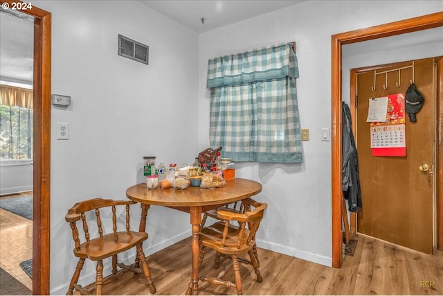 dining space with wood finished floors, visible vents, and baseboards