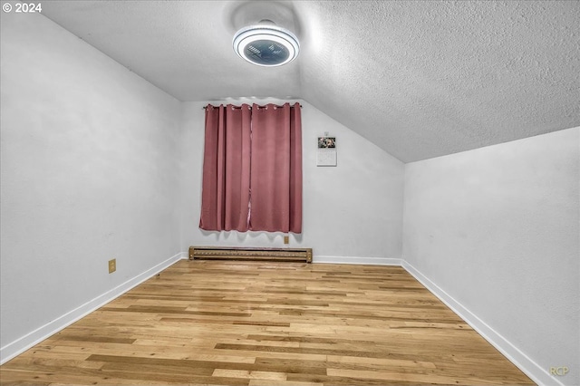 bonus room with a baseboard radiator, lofted ceiling, a textured ceiling, light wood-type flooring, and baseboards