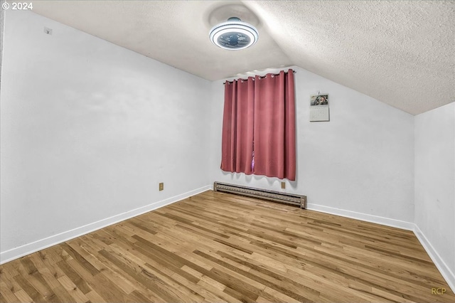 additional living space with lofted ceiling, a baseboard radiator, a textured ceiling, wood finished floors, and baseboards