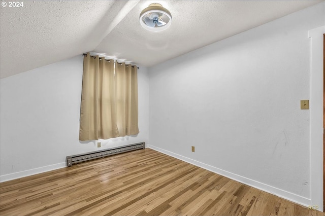 additional living space with lofted ceiling, baseboard heating, a textured ceiling, wood finished floors, and baseboards