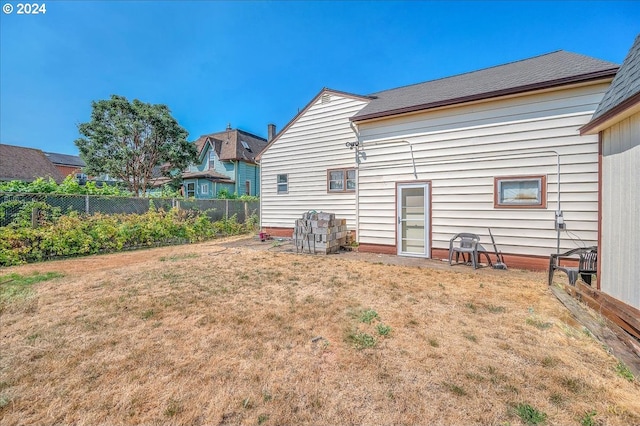 rear view of house with a lawn and fence