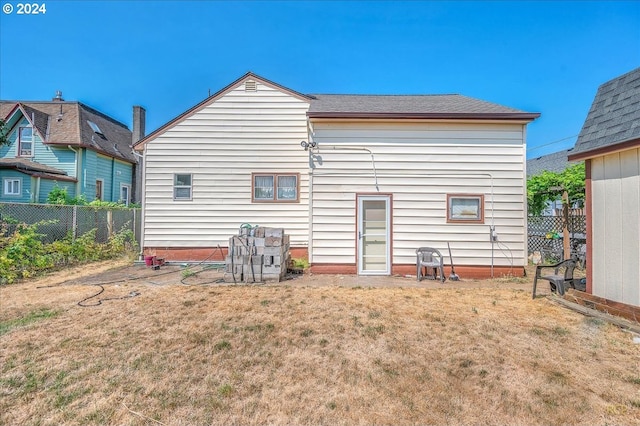 rear view of house with a lawn and fence