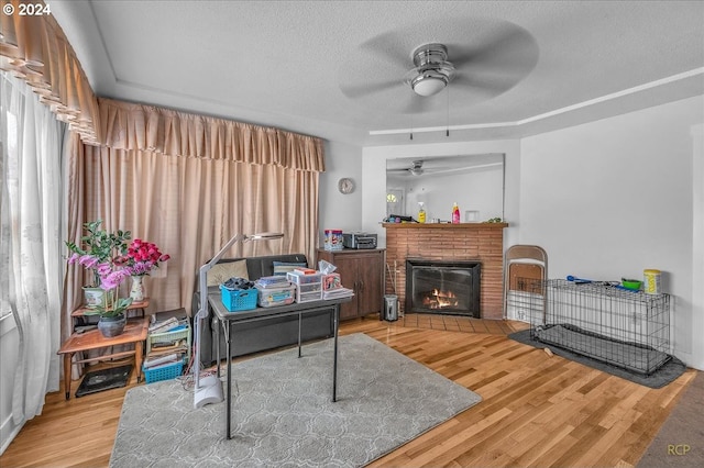 office with a brick fireplace, ceiling fan, a textured ceiling, and wood finished floors