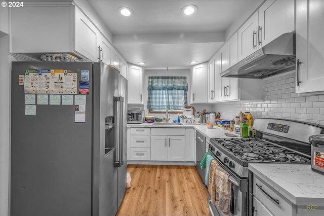 kitchen with appliances with stainless steel finishes, a sink, white cabinetry, and under cabinet range hood