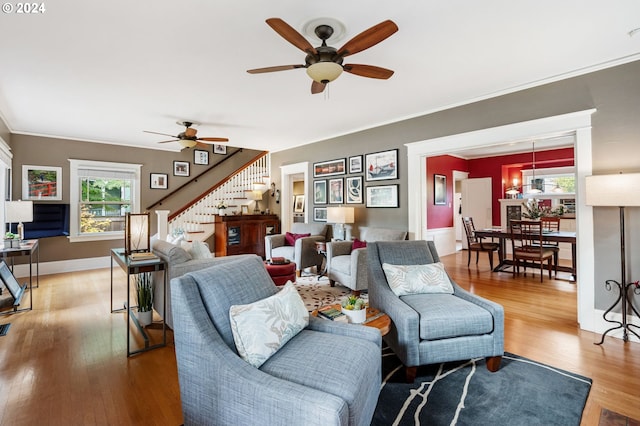 living room with ornamental molding, wood-type flooring, and ceiling fan