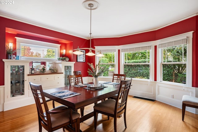 dining room featuring light hardwood / wood-style floors, a healthy amount of sunlight, and ornamental molding