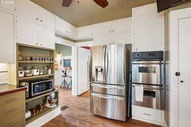 kitchen with white cabinets, stainless steel appliances, wood-type flooring, and ceiling fan