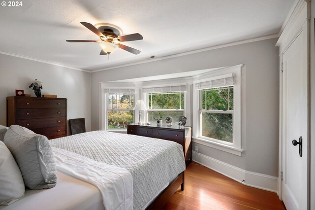 bedroom with crown molding, wood-type flooring, and ceiling fan