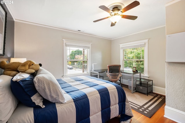 bedroom featuring ceiling fan, crown molding, multiple windows, and light wood-type flooring