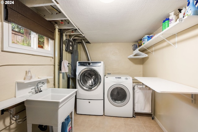 laundry room featuring a sink, light tile patterned floors, independent washer and dryer, and a textured ceiling