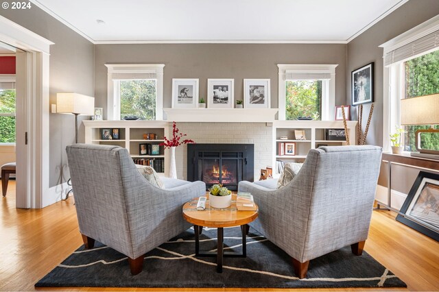 living room featuring light hardwood / wood-style flooring, crown molding, plenty of natural light, and a brick fireplace