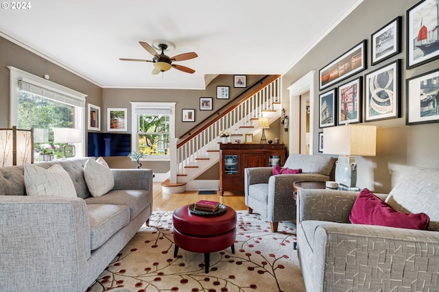 living area featuring ornamental molding, stairway, wood finished floors, and a ceiling fan