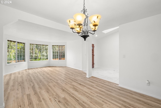 empty room featuring a chandelier and light hardwood / wood-style floors