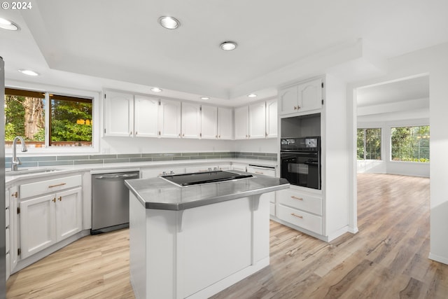 kitchen with a center island, black appliances, sink, white cabinetry, and light wood-type flooring