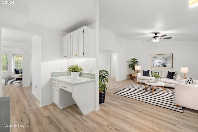 kitchen featuring ceiling fan, vaulted ceiling, white cabinetry, and light hardwood / wood-style floors