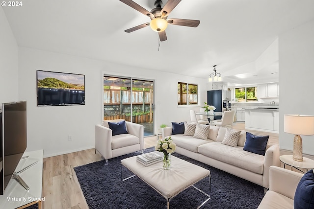 living room with light wood-type flooring, lofted ceiling, and ceiling fan with notable chandelier