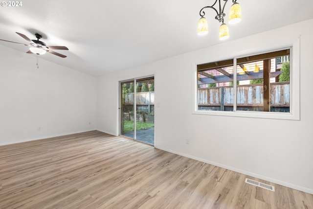 unfurnished room with lofted ceiling, ceiling fan with notable chandelier, and light hardwood / wood-style flooring