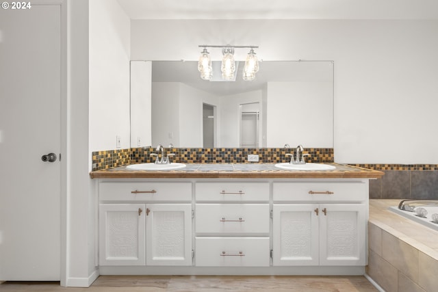 bathroom featuring vanity, decorative backsplash, and tiled tub