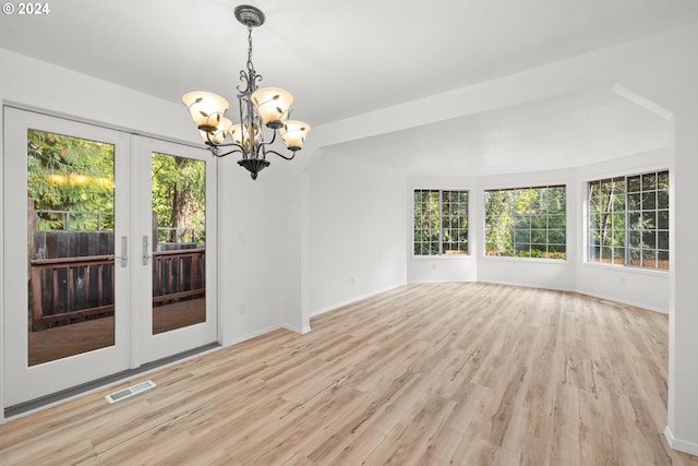 unfurnished room with light wood-type flooring, french doors, and a chandelier