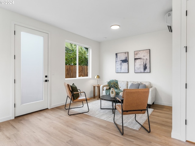 sitting room featuring light hardwood / wood-style flooring and an AC wall unit