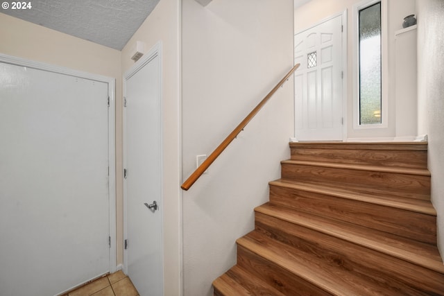 stairway featuring tile patterned floors and a textured ceiling