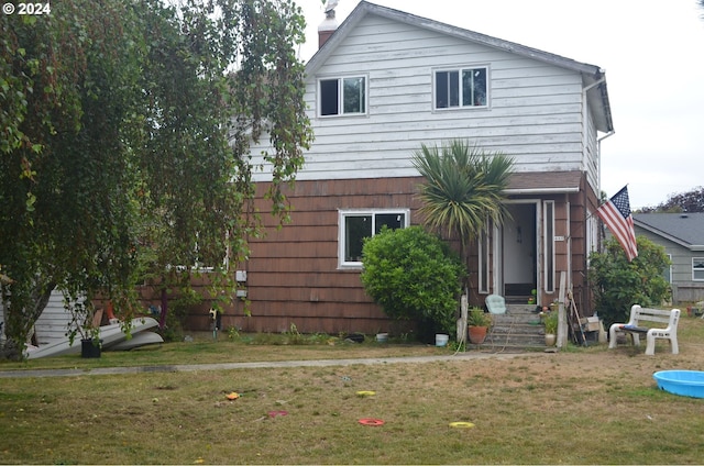 rear view of property featuring a lawn