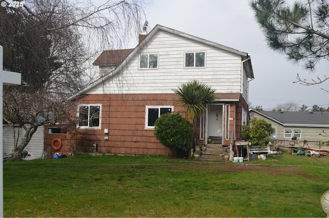 back of property with a chimney and a yard