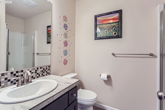 bathroom with tasteful backsplash, vanity, a shower with shower door, and toilet