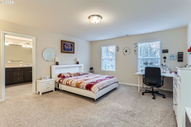 bedroom featuring connected bathroom, light colored carpet, and sink