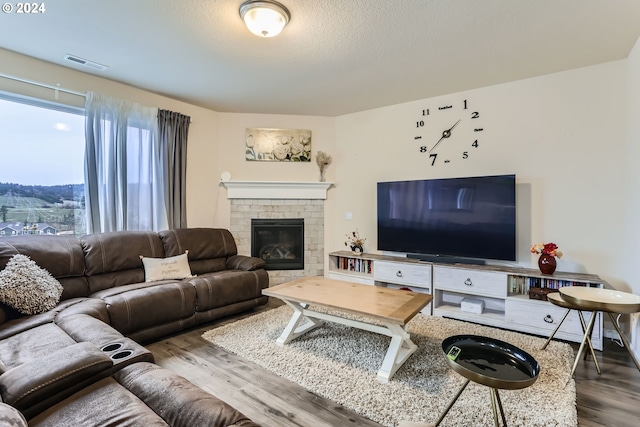 living room featuring hardwood / wood-style flooring, a textured ceiling, and a fireplace