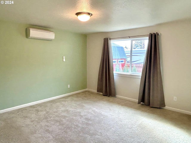 spare room with a textured ceiling, carpet flooring, and a wall mounted air conditioner