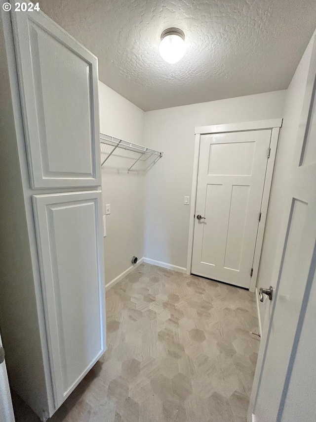 clothes washing area featuring laundry area, baseboards, and a textured ceiling