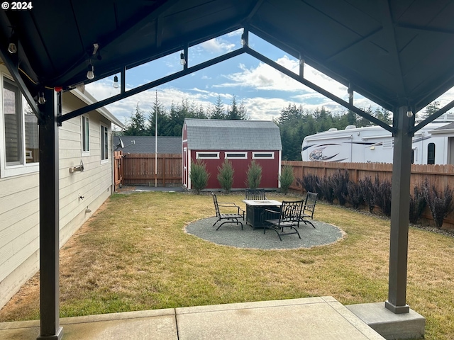 view of yard with an outdoor fire pit, a fenced backyard, an outdoor structure, a gazebo, and a storage unit