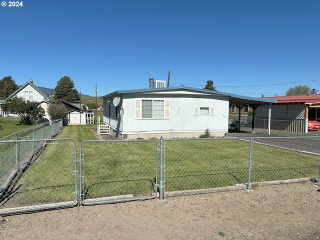 view of front facade with a front yard, a storage unit, and a carport